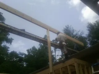Carpenter setting a ridge beam over a new addition frame — Ice Dam Removal by Roofing Brothers in Snellville