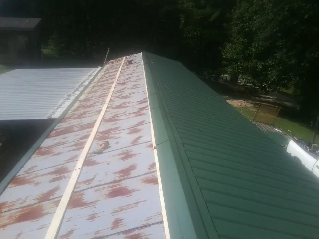 Old rusted panels beside newly installed green metal roofing — Wind Damage Roof Repair by Roofing Brothers in Snellville