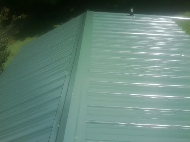 New green metal panels meeting at the ridge of a roof — Flat Roof Repair work by our crew in Snellville