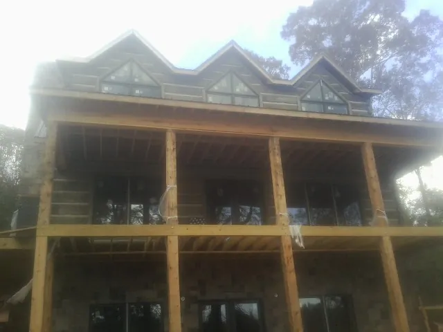 Dormers and porch framing on a large log home under construction — Roof Coating work by our crew in Snellville