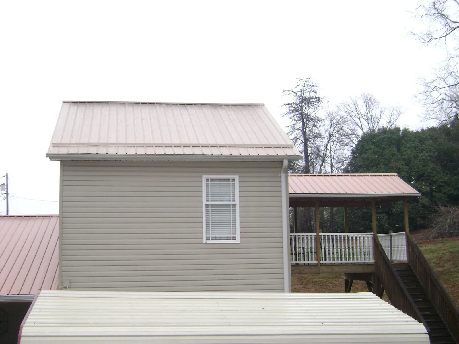 Tan metal roofs on a two story addition and attached porch, from a Roof Replacement job in Snellville