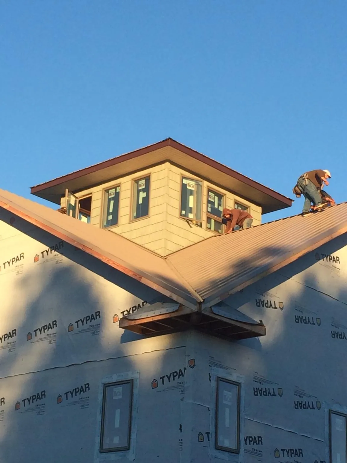 Roofers working around a rooftop cupola on a new metal roof at sunset — Roof Waterproofing in Snellville by Roofing Brothers
